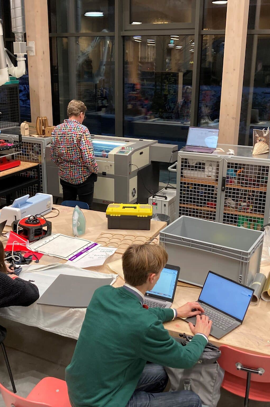 Man ser nogle unge der arbejder med robotter og pc'er.
